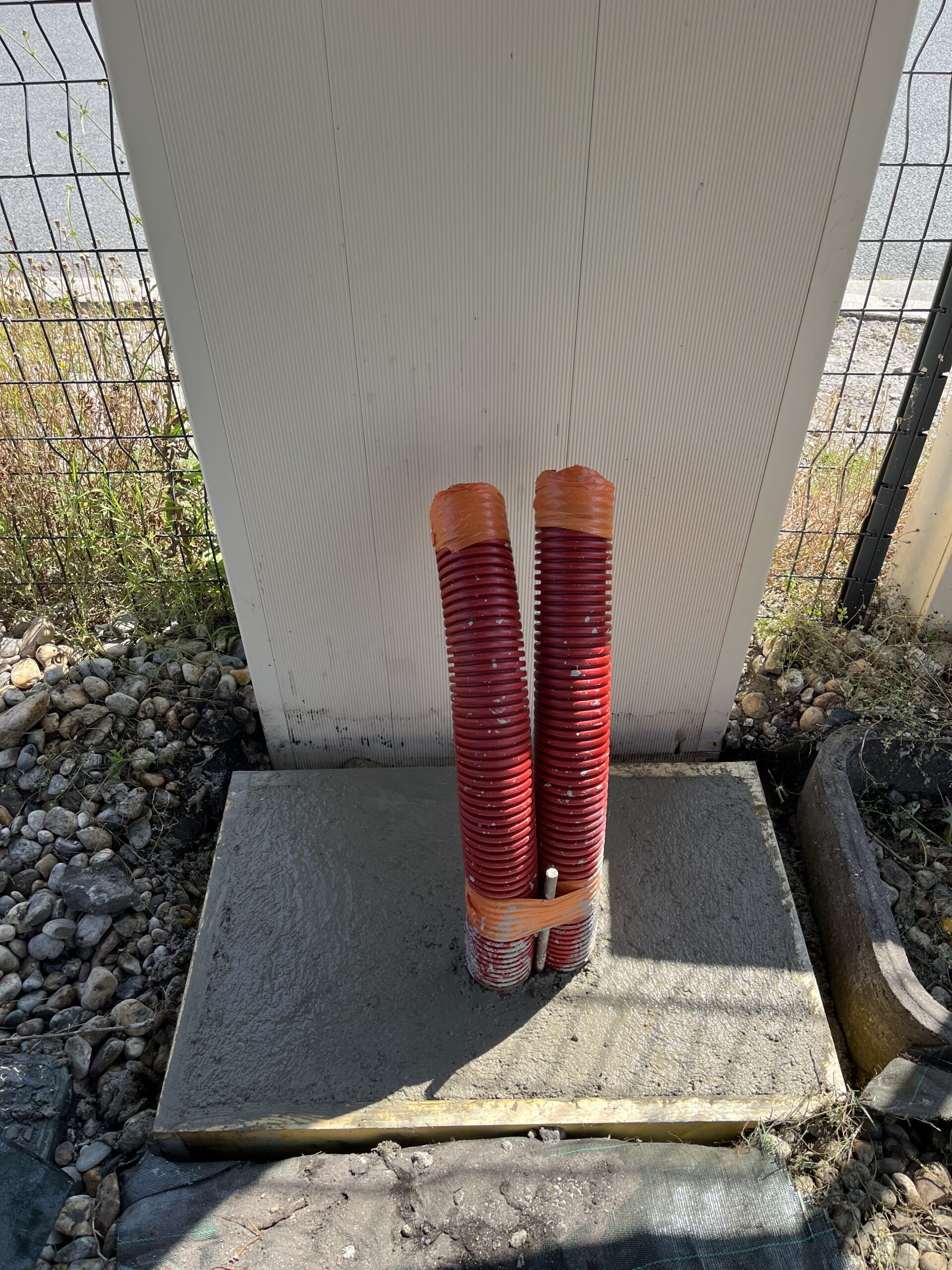 Photo d’une tranchée avec une gaine électrique posée, entourée de sable et d’un grillage avertisseur à Villeneuve-sur-Lot (47300).