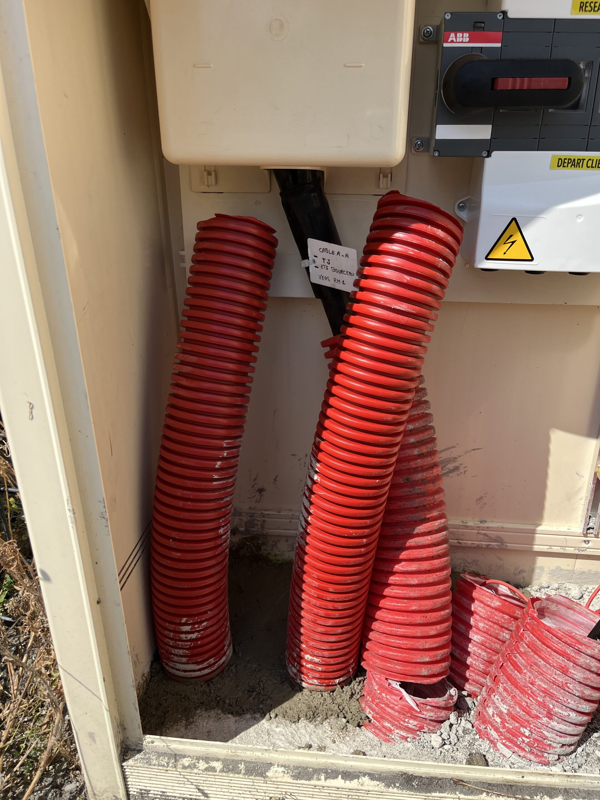 Photo d’une tranchée avec une gaine électrique posée, entourée de sable et d’un grillage avertisseur à Villeneuve-sur-Lot (47300).