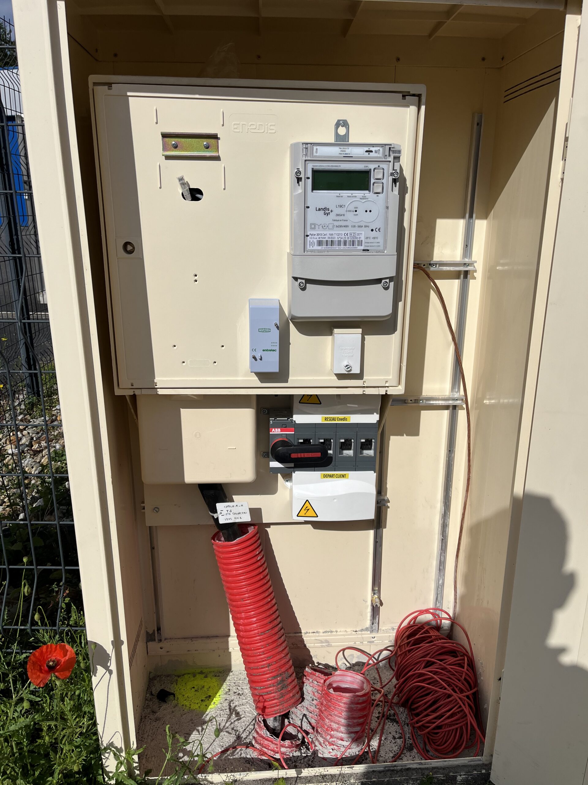 Photo d’une tranchée avec une gaine électrique posée, entourée de sable et d’un grillage avertisseur à Villeneuve-sur-Lot (47300).