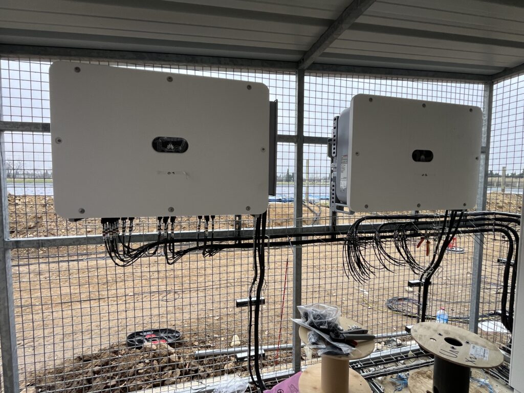 Électricien Perpignan 66000 en train de raccorder un onduleur à une installation photovoltaïque flottante, avec coffrets étanches et câblage sécurisé en zone humide.