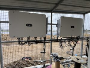 Électricien Perpignan 66000 en train de raccorder un onduleur à une installation photovoltaïque flottante, avec coffrets étanches et câblage sécurisé en zone humide.