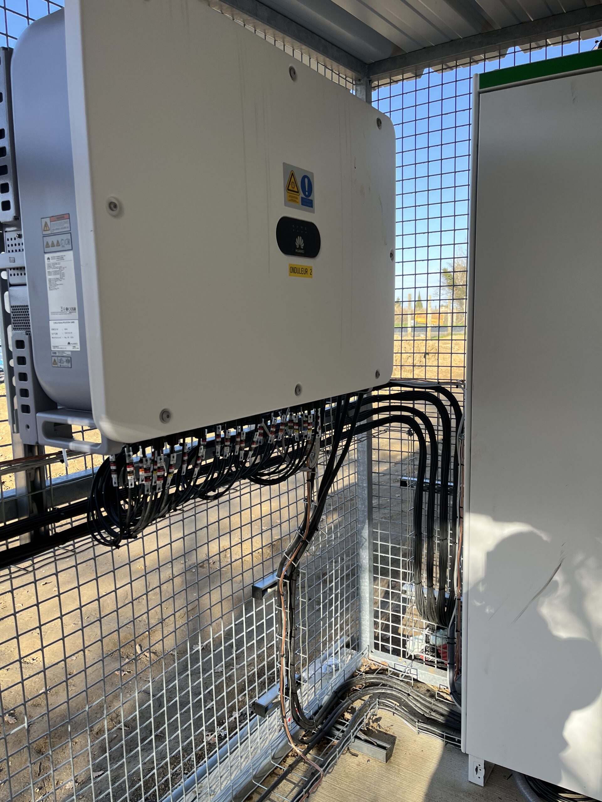 Électricien Perpignan 66000 en train de raccorder un onduleur à une installation photovoltaïque flottante, avec coffrets étanches et câblage sécurisé en zone humide.