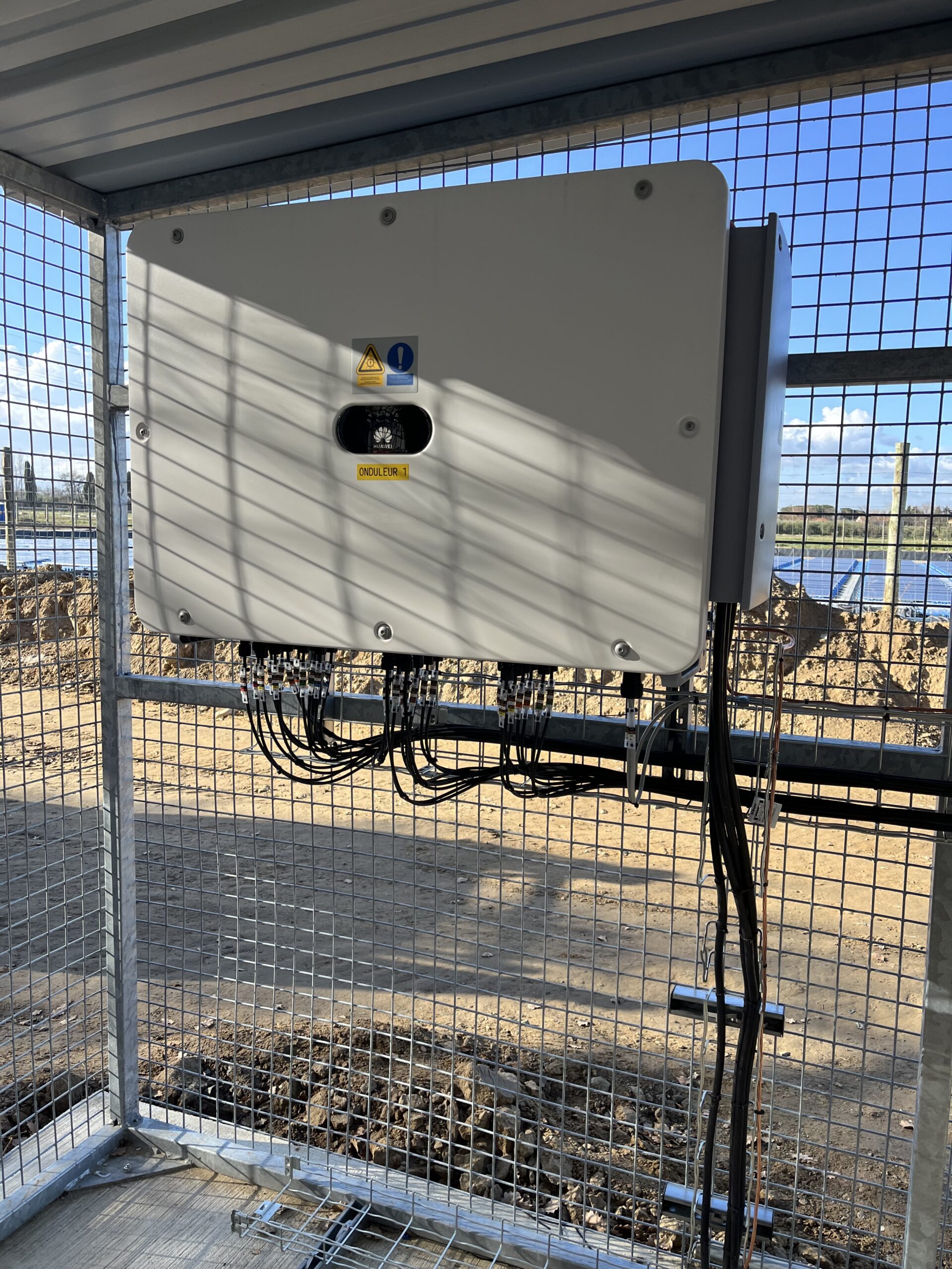 Électricien Perpignan 66000 en train de raccorder un onduleur à une installation photovoltaïque flottante, avec coffrets étanches et câblage sécurisé en zone humide.